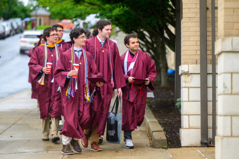 Graduates smile on their way to Commencement