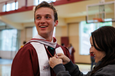 A graduate gets help with their gown.
