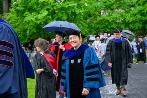 A faculty member walks in the rain.