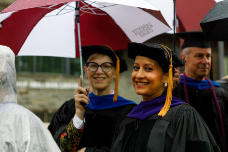 Two members of the Board of Trustees share an umbrella.