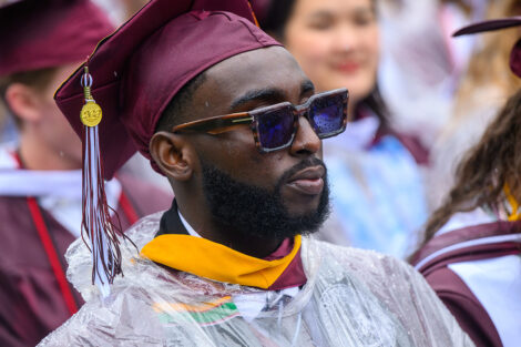 A student wears sunglasses in the crowd of graduates.