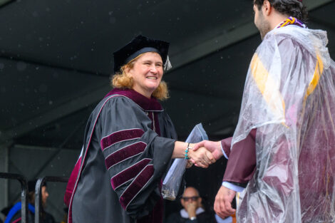 A graduate shakes President Nicole Hurd's hand.