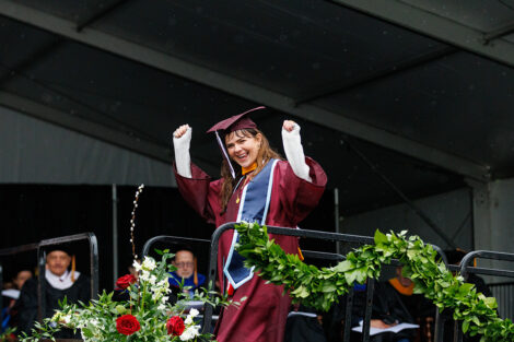 A graduate, covered in rain, smiles at the crowd.