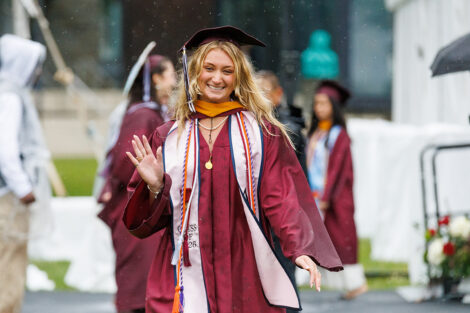 A graduate waves in the rain.