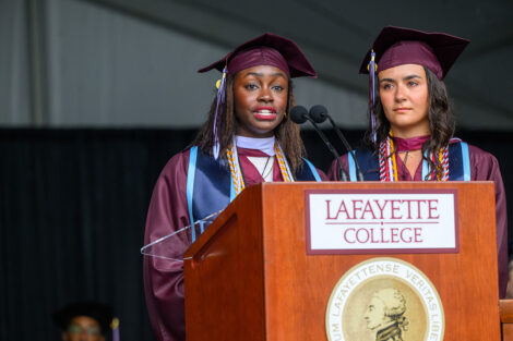 Two graduates speak at the podium.