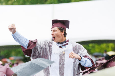 A graduate celebrates in the middle of the crowd.
