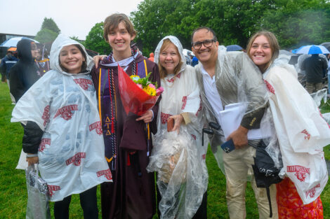 A graduate smiles with their family.