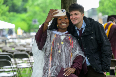 A graduate smiles with a family member for a selfie