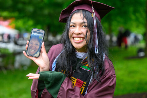 A graduate holds up her phone with a loved one on facetime.
