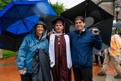 A graduate smiles with their family.