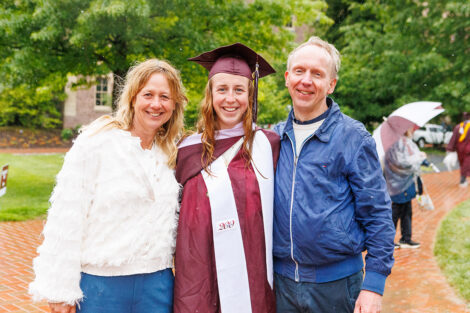 A graduate smiles with their family.