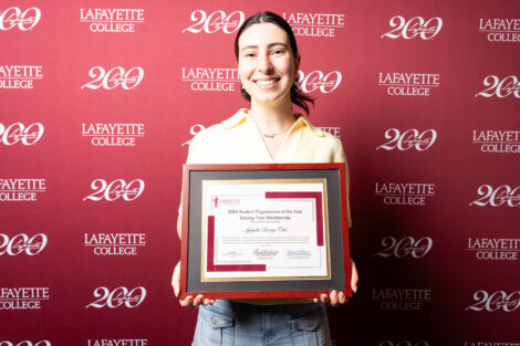 Christina Kouyoumdji '26 is holding a framed award.