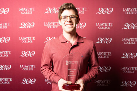 Bram Halpert ’27 is holding a glass award.