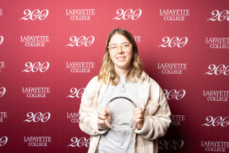 Catherine McCarron ’28 is holding a round glass award.