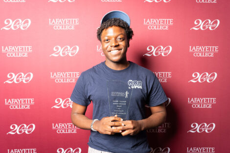 Clovis Nkamga ’29 is holding a glass award.