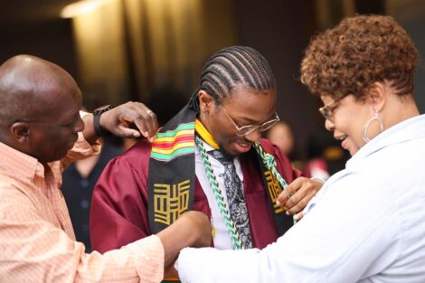 A student adjusts their stole at the Donning of the Kente