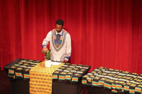 A person waters a plant at the Donning of the Kente