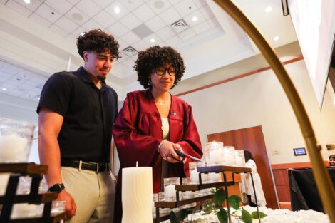 A student lights a candle at Unidos en Celebración
