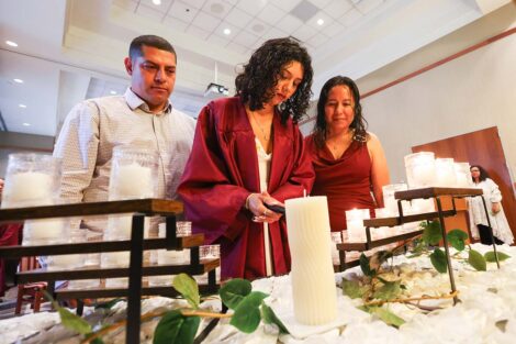 A student lights a candle at Unidos en Celebración