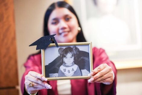 A student holds up a photo of their younger self