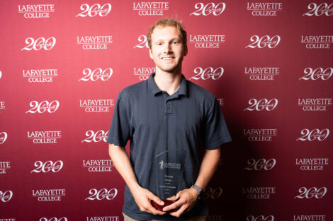 Robert McClosky ’26 is holding a glass award.
