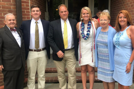 A family of six is standing and smiling at the camera.