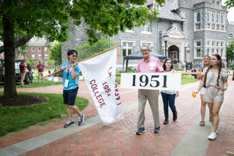 Alumni walk with a 1951 flag and a Lafayette College flag.