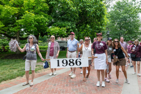 Members of the Class of 1986 carry the white sign in the parade. The sign reads 1986.