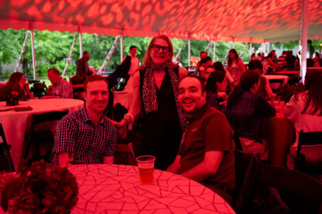 Three alumni are seated under the Reunion tent. They are basked in maroon leopard print.