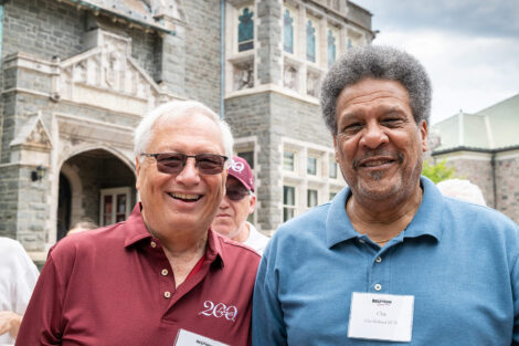 Two alumni are in front of Hogg Hall.
