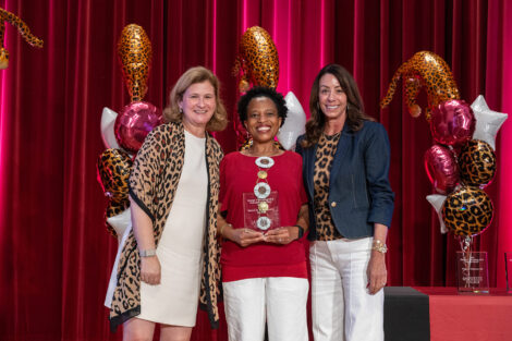 Bessie is standing on stage with President Hurd and Fran Della Badia. She is holding a glass award.