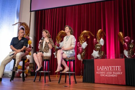 Board Chair Robert E. Sell ’84, H’18, President Nicole Farmer Hurd, and Provost Laura McGrane are seated on leopard stools on a stage.
