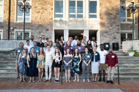 A large group of alumni stand outside Farinon College Center for a class photo.