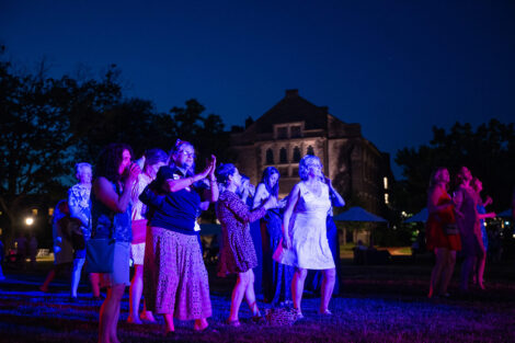A group of alumni and staff dance on the Quad.