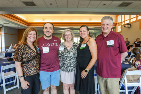 Professor Nancy Waters (center) stands with alumni. She is smiling at the camera.