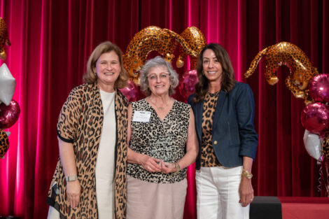 Prof. Nancy McCreary Waters is holding a glass award. She standing on stage with President Hurd and Fran Della Badia.