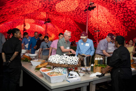 Alumni eat lunch under a tent that has leopard print lights on the ceiling.