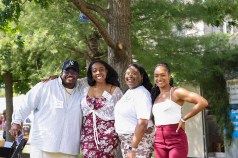 A group of four alumni pose outside.