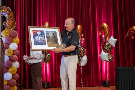 Robert E. Sell ’84, H’18 is holding a framed picture.