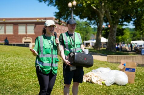 Sam Comas and another volunteer speak into a microphone connected to a speaker.