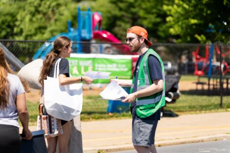 A volunteer in a green vest speaks with a shopper outside at West Ward Sale.