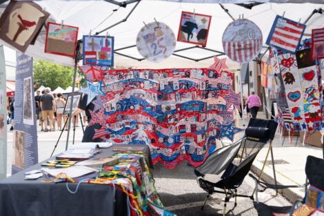 A fourth grade red, white, and blue quilt hangs from an outdoor tent during Heritage Day in Easton.