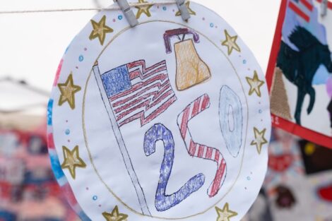 A round picture that features a flag and liberty bell hangs from an outdoor tent.