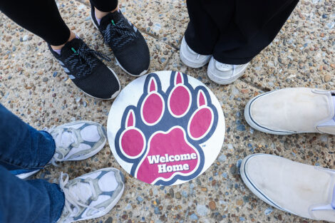Students' feet encircle a Leopard paw print decal which welcomed home incoming students.