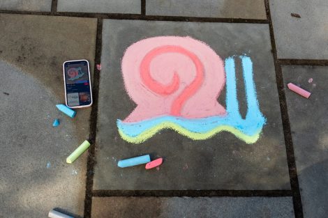 A chalk design of a snail is featured on the sidewalk during ChalkFest.